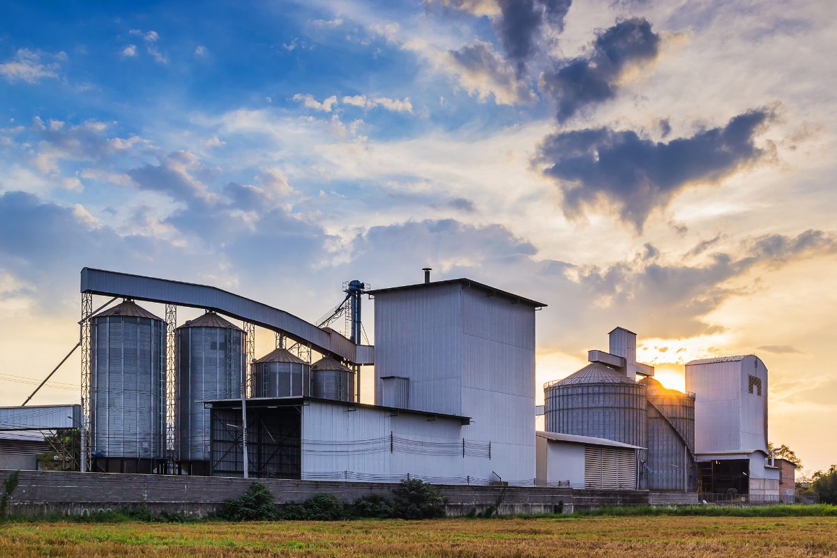 Feed mill with silos and enclosed conveyor spouting at sunset