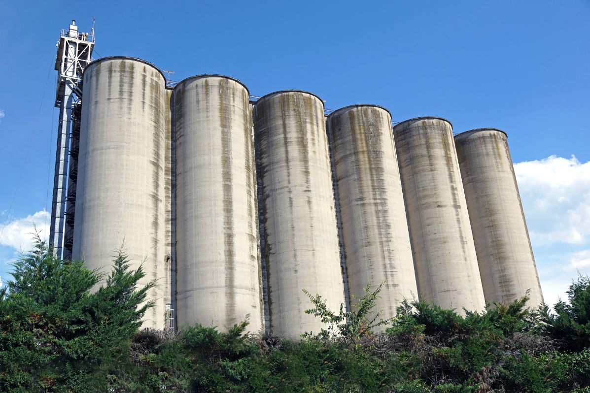 Tall concrete cement silos with an elevator tower alongside